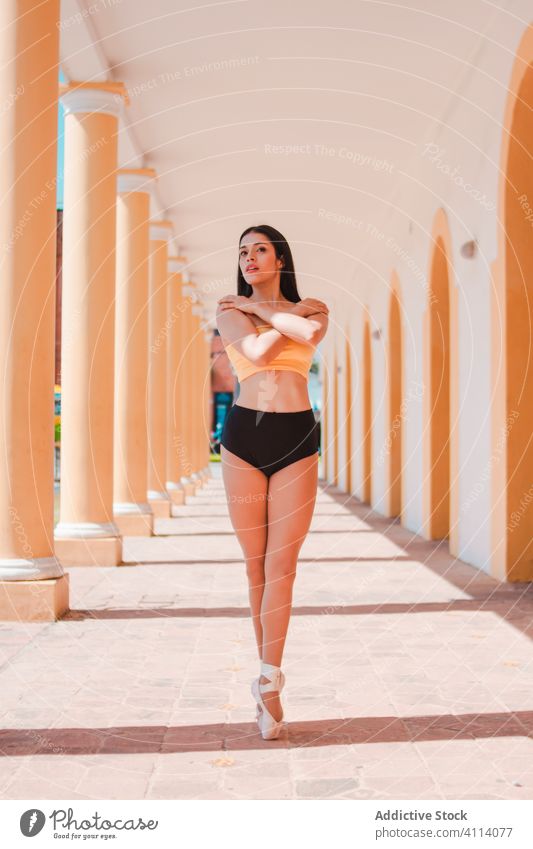 Slim ballerina dancing near colonnade woman dance ballet arms crossed building grace concept young slim female elegant pillar passage architecture perform