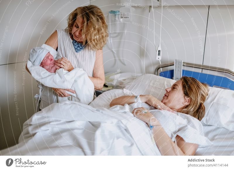 Woman visiting daughter with newborn baby in hospital mother grandmother women care bed greeting clinic happy neonatal kid medicine parent multi generational