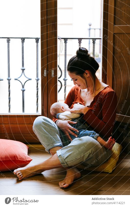 Happy mother breastfeeding baby near window home happy love rest cozy sit woman cute room hug embrace smile child kid childhood little care together parent