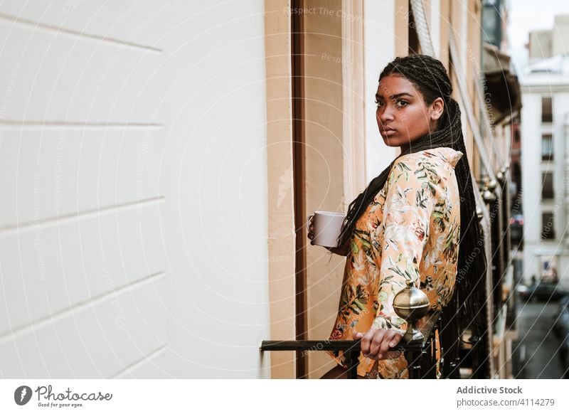 Young woman with cup of coffee standing on balcony calm drink casual home tranquil thoughtful relax young african american black ethnic brunette house city