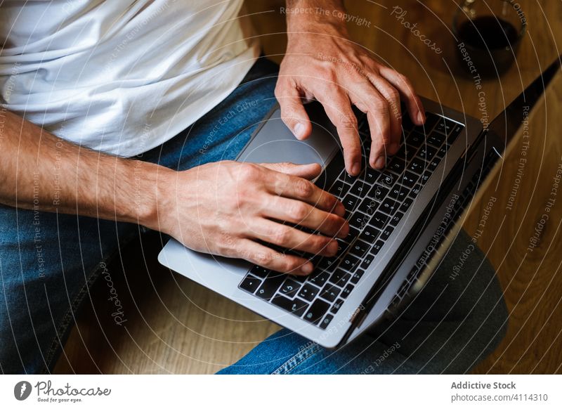 Bearded freelancer using laptop at home man hipster sitting typing drink floor project modern male casual device work internet lifestyle gadget browsing data