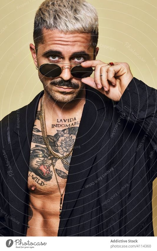 Provocative shirtless man in black coat and sunglasses macho cool trendy brutal tattoo style fashion unshaven model personality muscular beard male ethnic