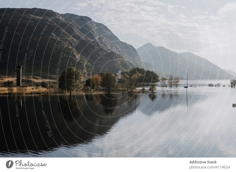 Calm lake reflecting rocky mountains reflection sunny landscape highland cloud tree calm tranquil water nature peaceful scotland shore travel tourism