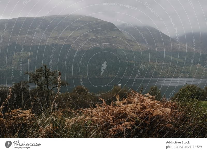 Foggy landscape with mountains and lake fog mist cloud rock highland range calm tranquil water nature cold peaceful scotland gloomy shore travel tourism