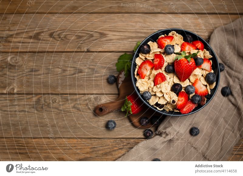 Fresh cornflakes served with strawberries and blueberries placed on wooden table breakfast strawberry blueberry cereal delicious fresh bowl organic healthy