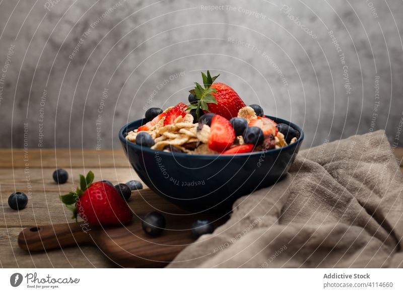 Fresh cornflakes served with strawberries and blueberries placed on wooden table breakfast strawberry blueberry cereal delicious fresh bowl organic healthy