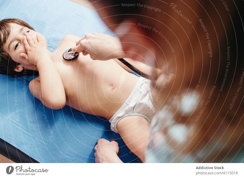 Doctor with stethoscope examining kid in clinic doctor examine cheerful smile hospital little boy lying couch chest respiratory patient health care medicine