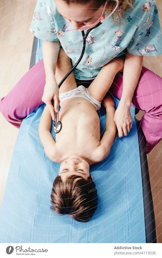 Doctor with stethoscope examining kid in clinic doctor examine cheerful smile hospital little boy lying couch chest respiratory patient health care medicine