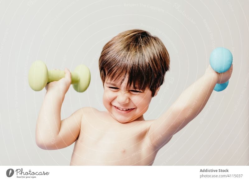 Cheerful little boy with dumbbells kid healthy happy active smile cheerful energy positive child exercise lifestyle joy training childhood glad health care