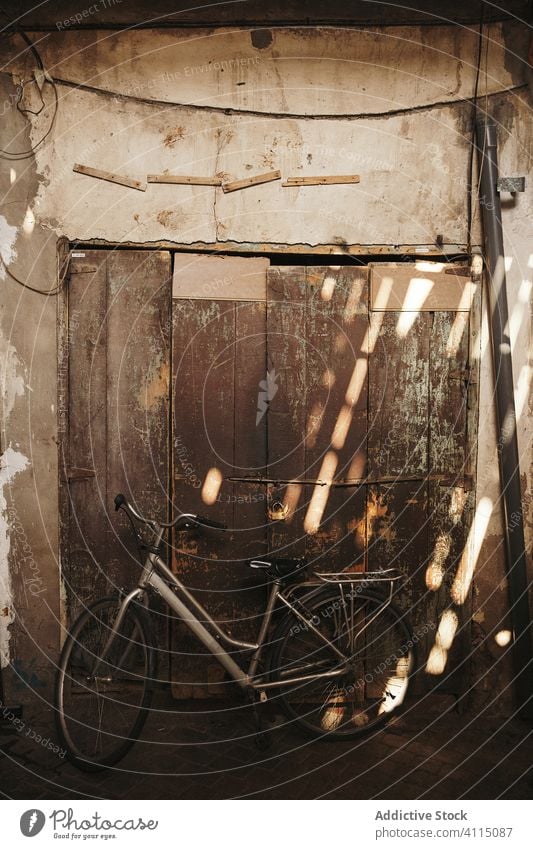 Old bicycle near shabby wall in sunbeams old retro weathered grunge aged house vintage door building wooden street transport entrance parked vehicle style rough