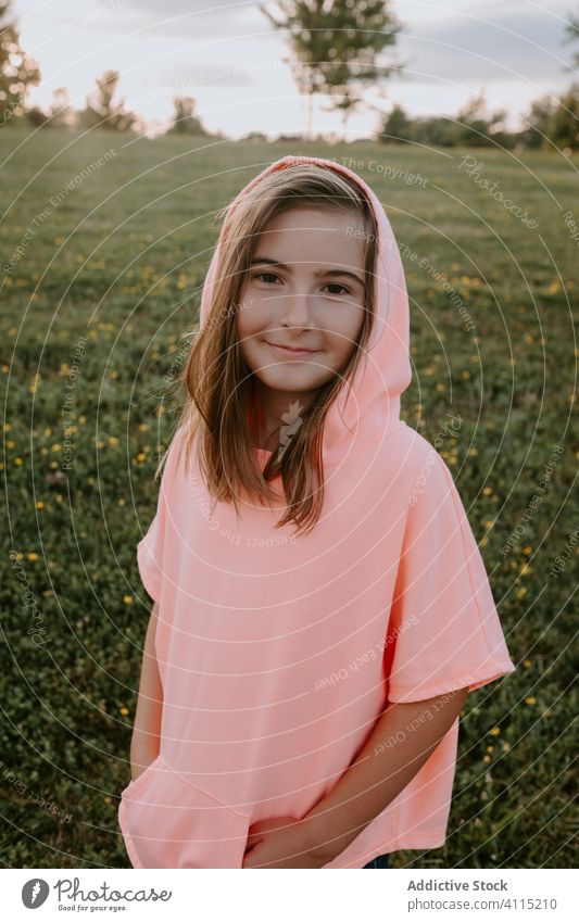 Adorable little girl standing in a park looking at camera summer countryside path casual kid cheerful smile preteen pathway happy female child enjoy activity