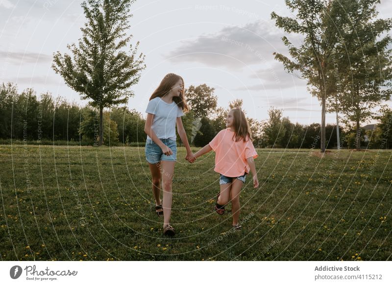 Happy sisters having fun in summer countryside kid nature together happy girl cheerful run teen teenage green meadow sibling friend smile relationship field joy