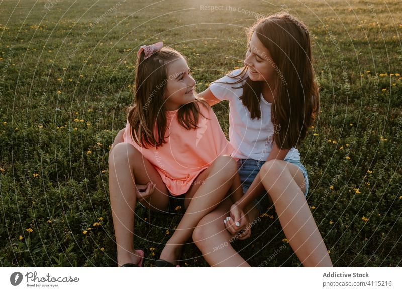 Happy kids hugging on green meadow sister nature together happy sit grass summer girl countryside cheerful teen teenage sibling friend rest embrace smile