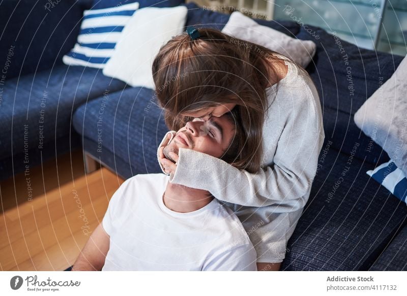 Young couple in love resting together at home hug relationship romantic casual sofa relax young positive happy cozy embrace smile lifestyle affection