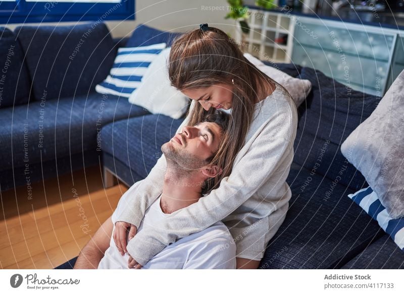 Young couple in love resting together at home hug relationship romantic casual sofa relax young positive happy cozy embrace smile lifestyle affection