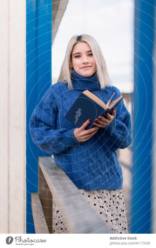 Pensive woman near striped wall book thoughtful pensive read style standing dream relax casual female blonde smile rest enjoy charming knowledge learn peaceful