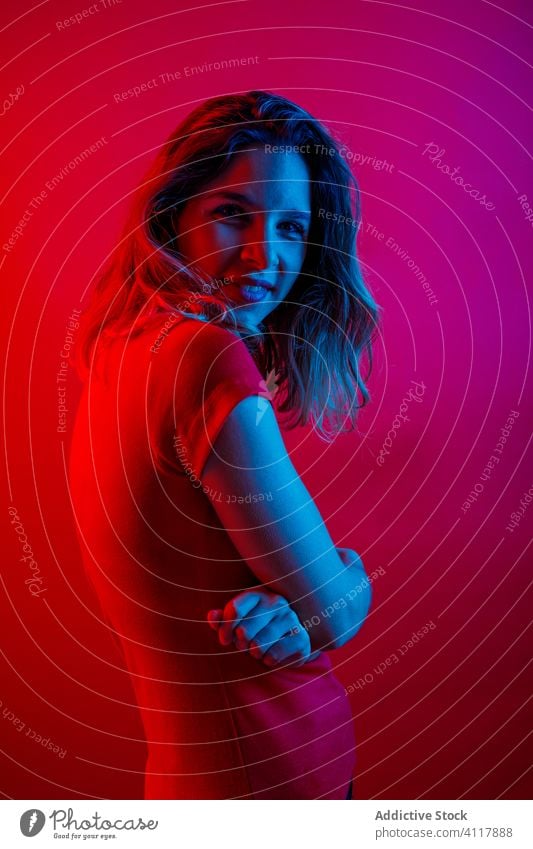 Positive woman with crossed arms under neon light positive smile arms crossed illuminate blue light colorful model vibrant female style young vivid trendy dark