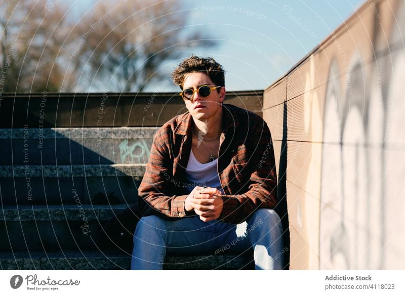 Young man resting on steps sit street urban city modern hipster male young sunny style casual millennial trendy town lifestyle relax staircase building guy