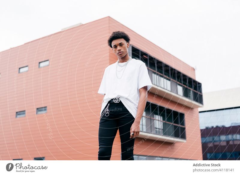 Trendy black guy standing against city building man style trendy street urban accessory gangster cool modern fashion ethnic confident young african american