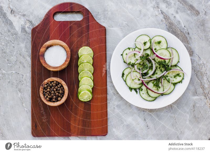 Seasoning ingredients on board and cucumber salad on plate vegetable seasoning onion herb cutting board salt pepper lime marble vegetarian mix dinner slice dish