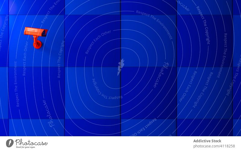 Red surveillance camera on blue background monitoring coronavirus control pandemic infected technology safety police guard security secure red looking observe