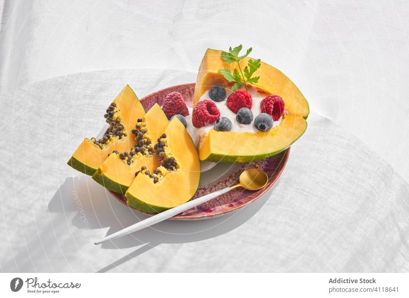 Papaya with yoghurt and berries papaya plate berry dessert spoon herb tropical piece ripe seed fresh food slice raspberry blueberry fruit cut healthy meal