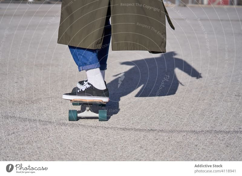 A Man skating on a skateboard on the road with his raincoat and city guy sports people concrete urban asphalt recreation sunny skateboarding street extreme