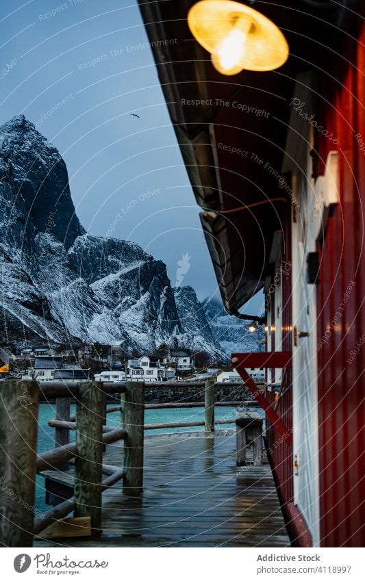 Small country house on lake in winter cottage pier shore foothill waterfront sky snow township countryside coast lofoten idyllic facade shoreline tranquil