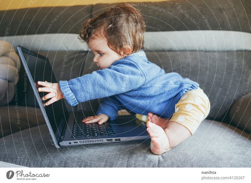 Little baby at home playing with a laptop technology progress future sofa furniture pc computer risk wifi social media new generation babyhood screen childhood