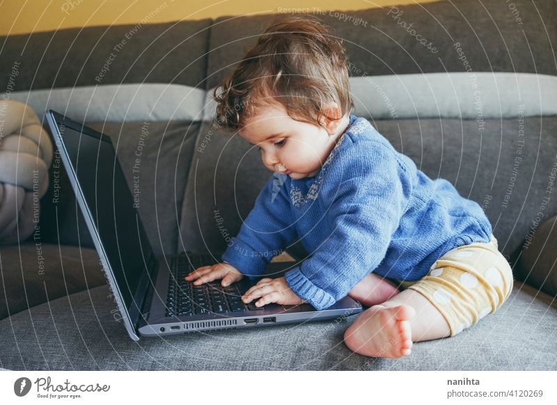 Little baby at home playing with a laptop technology progress future sofa furniture pc computer risk wifi social media new generation babyhood screen childhood