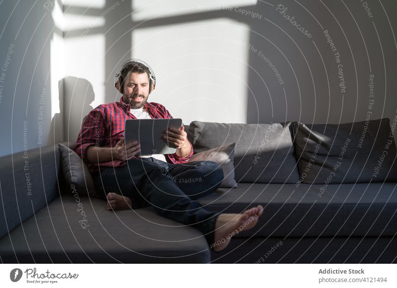 Young man listening to music at home young leisure casual headphones technology caucasian adult lifestyle happy sofa person relaxation modern room indoors