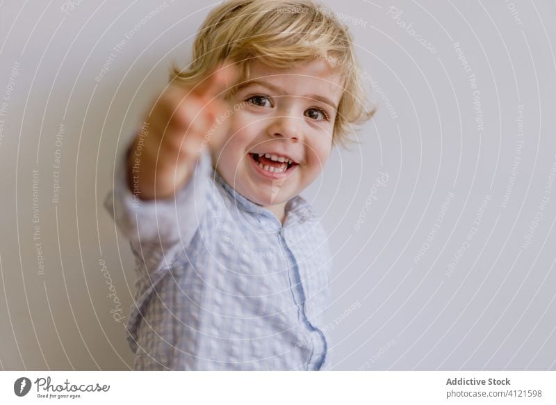 Delighted boy smiling and pointing at camera smile delight little kid adorable child content cheerful optimist cute childhood positive casual face expression