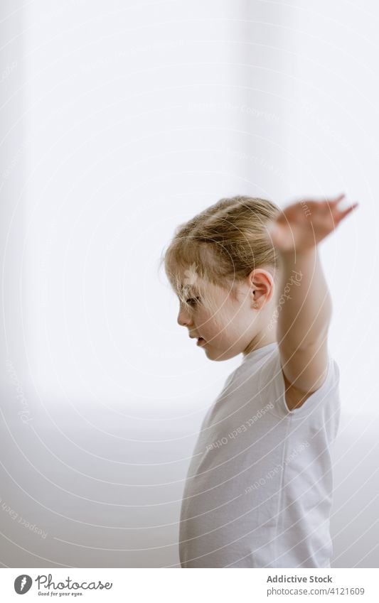 Happy girl doing morning exercises in living room little stretch arm kid warm up content happy adorable smile delight child cheerful optimist cute outstretch