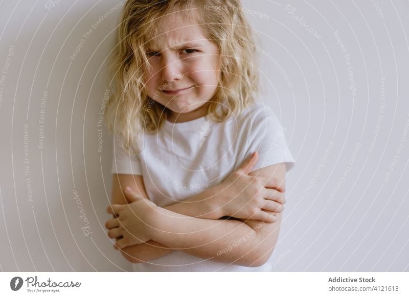 Little girl crying in studio weep naughty little child arms folded whine casual sad frown disappoint kid childhood face expression adorable cute t shirt blonde