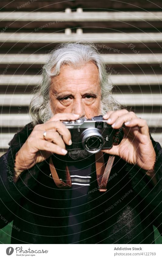 Senior stylish man taking photos on vintage camera senior style take photo city retro trendy photo camera photographer male elderly aged gray hair long hair