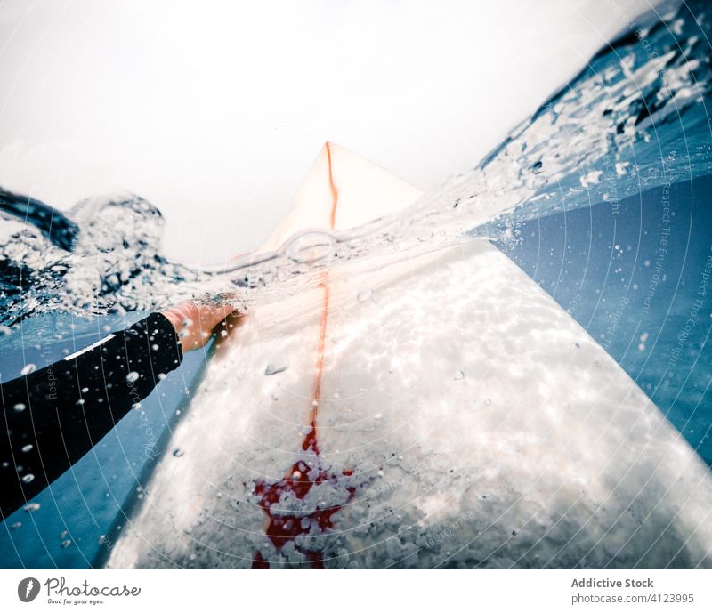 Crop surfer on board in sea water surfboard sink splash clean float fuerteventura spain canary islands ride ocean lifestyle extreme hobby sport wave recreation