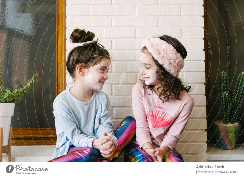 Happy little sisters having funny spa day at home children face mask laugh alike together playful skin care pajama happy relax scream childhood enjoy positive