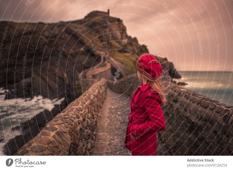 Woman walking on stone bridge surrounded by sea in Basque Country tourist woman seashore spain warm travel explore island trip journey vacation tourism holiday