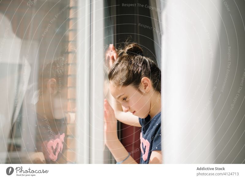 Lonely girl standing near window and looking outside sad lonely alone quarantine self isolation solitude wait miss dreamy hope social distancing thoughtful