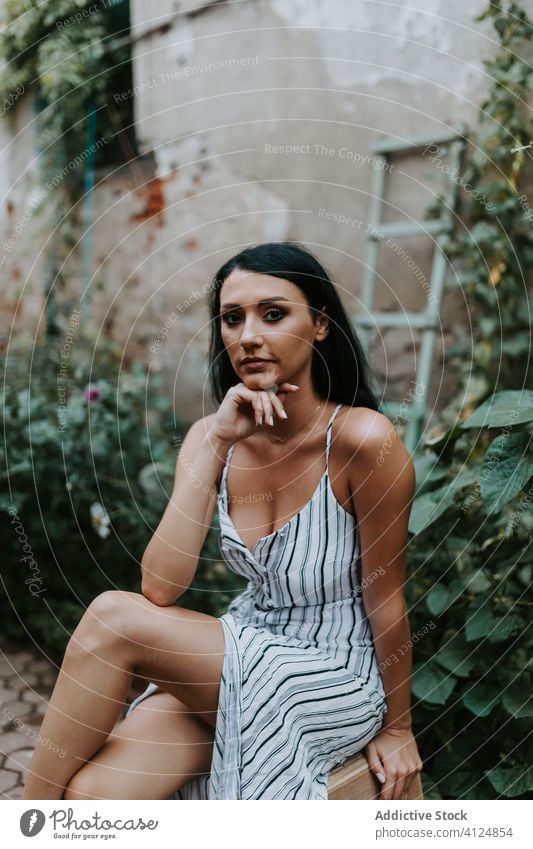 Young woman sitting on stool in garden old pavement style dress barefoot rest female path plant relax serene tranquil peaceful harmony calm summer idyllic flora