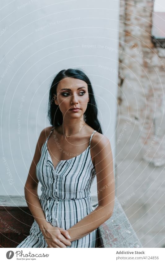 Young lady on balcony of old building woman rest shabby dress style young exterior female relax aged weathered terrace stripe serene architecture structure calm