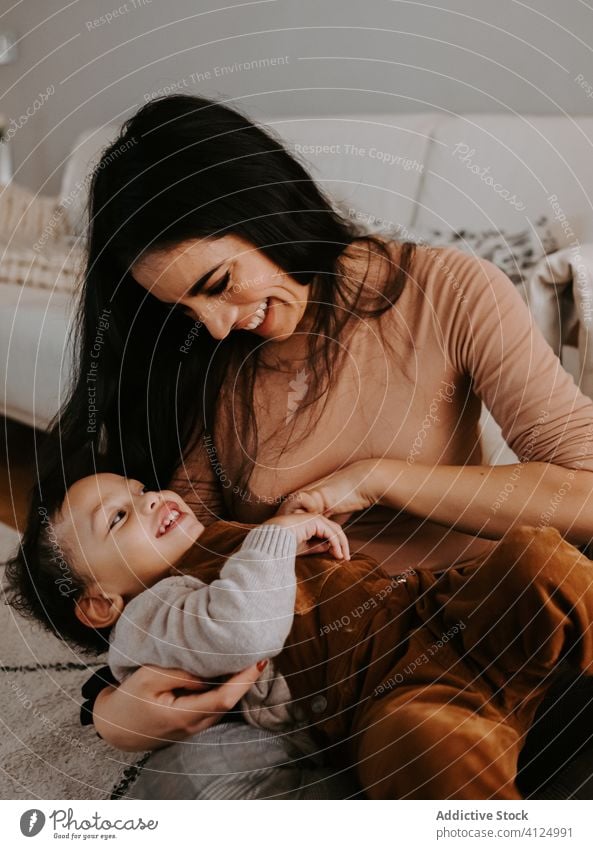 Cheerful loving mother hugging little son sitting on floor near Christmas tree cuddle christmas home playful cozy holiday smile child together kid parent