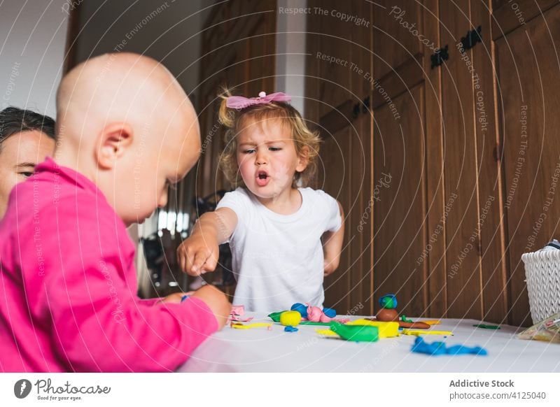 Cheerful siblings playing with modeling clay at home children colorful mother upbringing development preschool excited boy girl charming wow learn fun joy cute