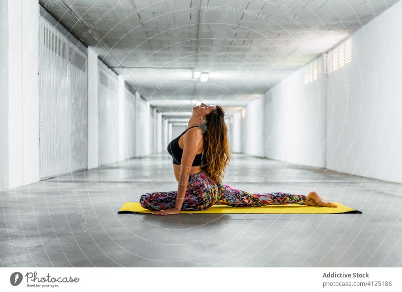 Woman practicing yoga on mat woman practice pigeon yoga eka pada rajakapotasana pose posture position balance eyes closed flexible concrete activity modern