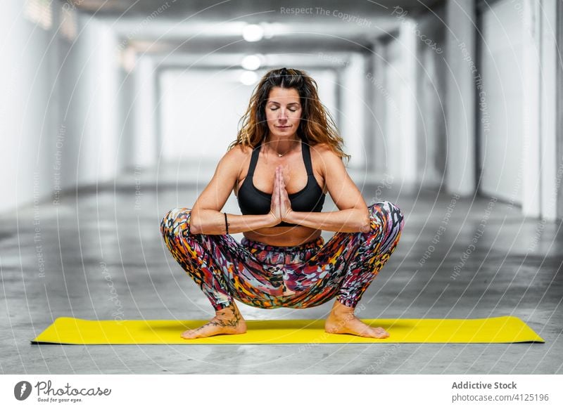 Calm woman meditating in Malasana pose yoga practice meditate malasana garland position balance calm garage tranquil female wellness lifestyle healthy flexible