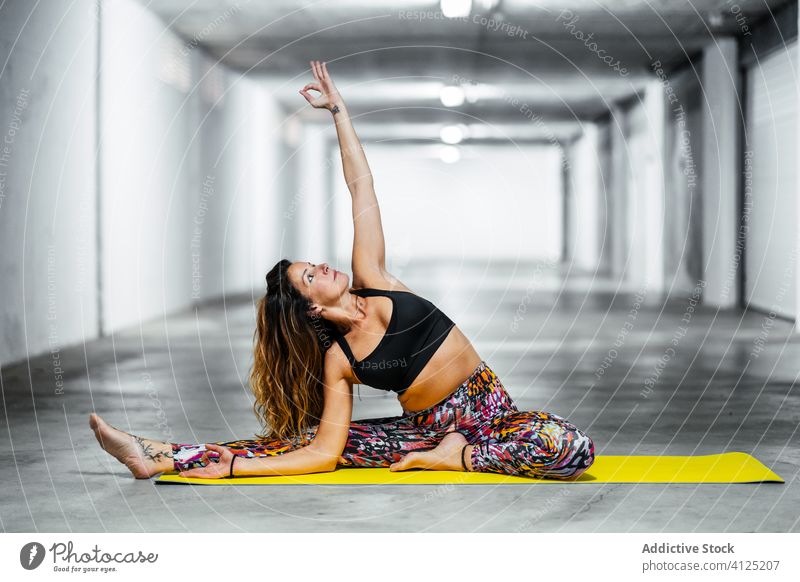 Woman practicing yoga on mat woman practice revolved head to knee parivrtta janu sirsasana pose posture position garage balance flexible hall concrete activity