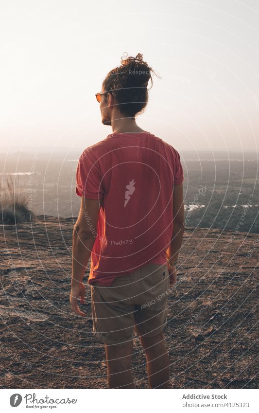 Distant man enjoying picturesque view from cliff admire explorer rocky incredible landscape sunset mountain travel sky idyllic observe harmony relax evening