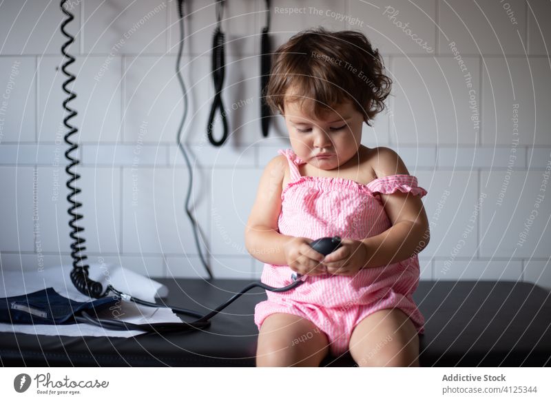 Curious little girl playing with tonometer in  clinic instrument patient toddler check up cute sit child equipment virus covid 19 coronavirus adorable pink