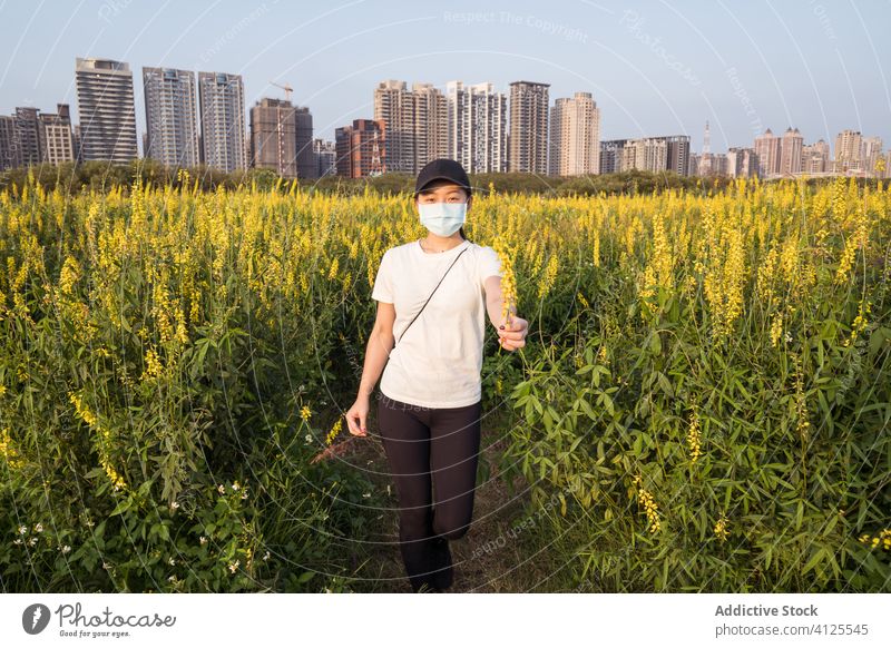 Ethnic woman in medical mask standing on green field protect coronavirus prevent covid nature young casual ethnic female modern safety health care covid 19