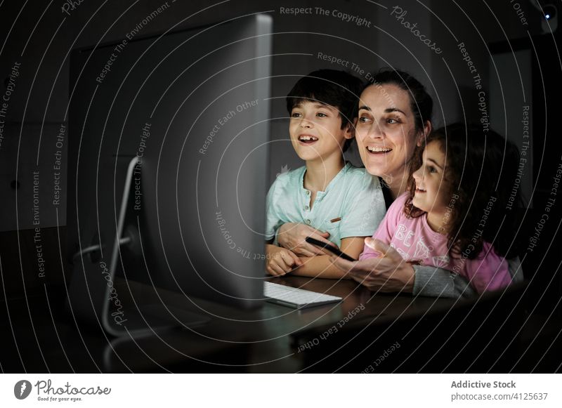 Cheerful woman with kids watching video on computer mother using smartphone together telework childcare happy cheerful home communicate gadget children mom